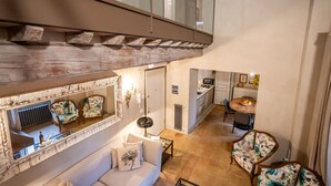 A spacious living area with a high ceiling, a large mirror, a sofa, and a dining table with chairs. - Beautiful apartment for 4 guests with WIFI, A/C and panoramic view (Cortona)