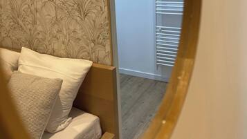 A bedroom with a bed, a nightstand, and a wall with a floral wallpaper pattern.