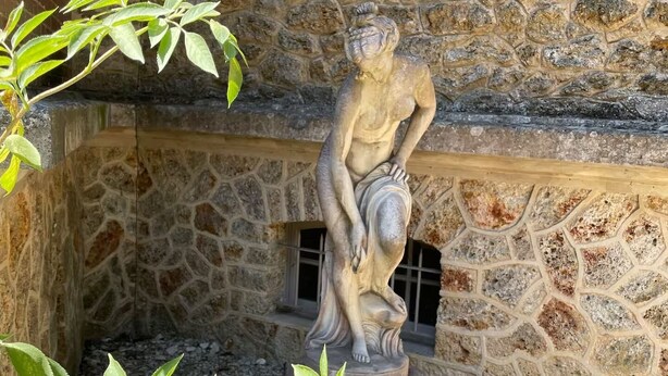 Un mur de pierre surmonté d’une statue représentant une figure assise.