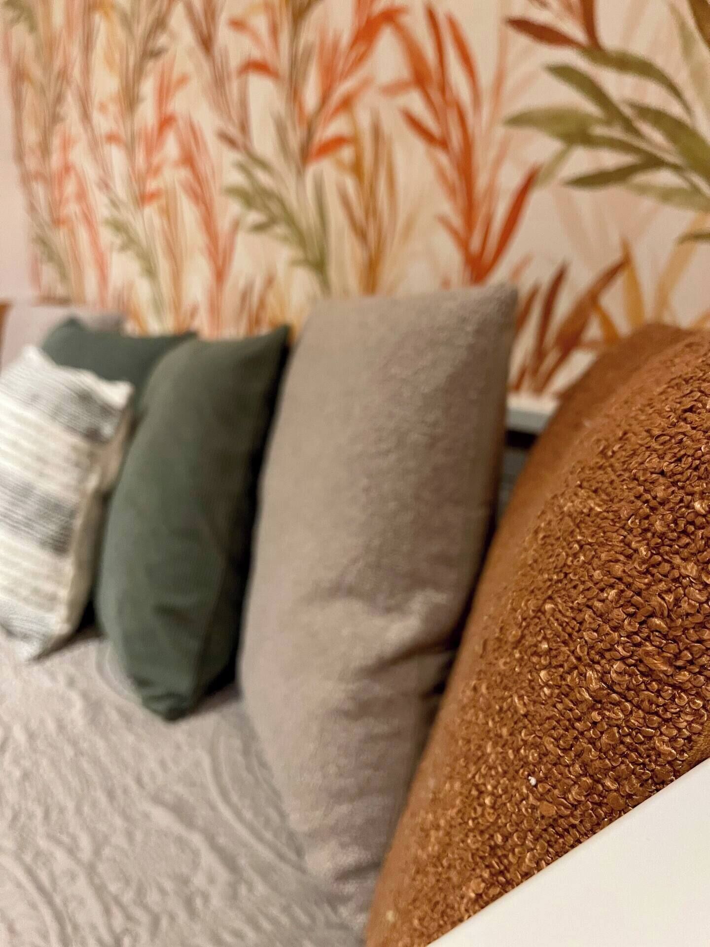 A room with a sofa, pillows, and a textured wall.