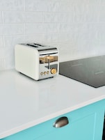 A white toaster with a stainless steel top on a white countertop.