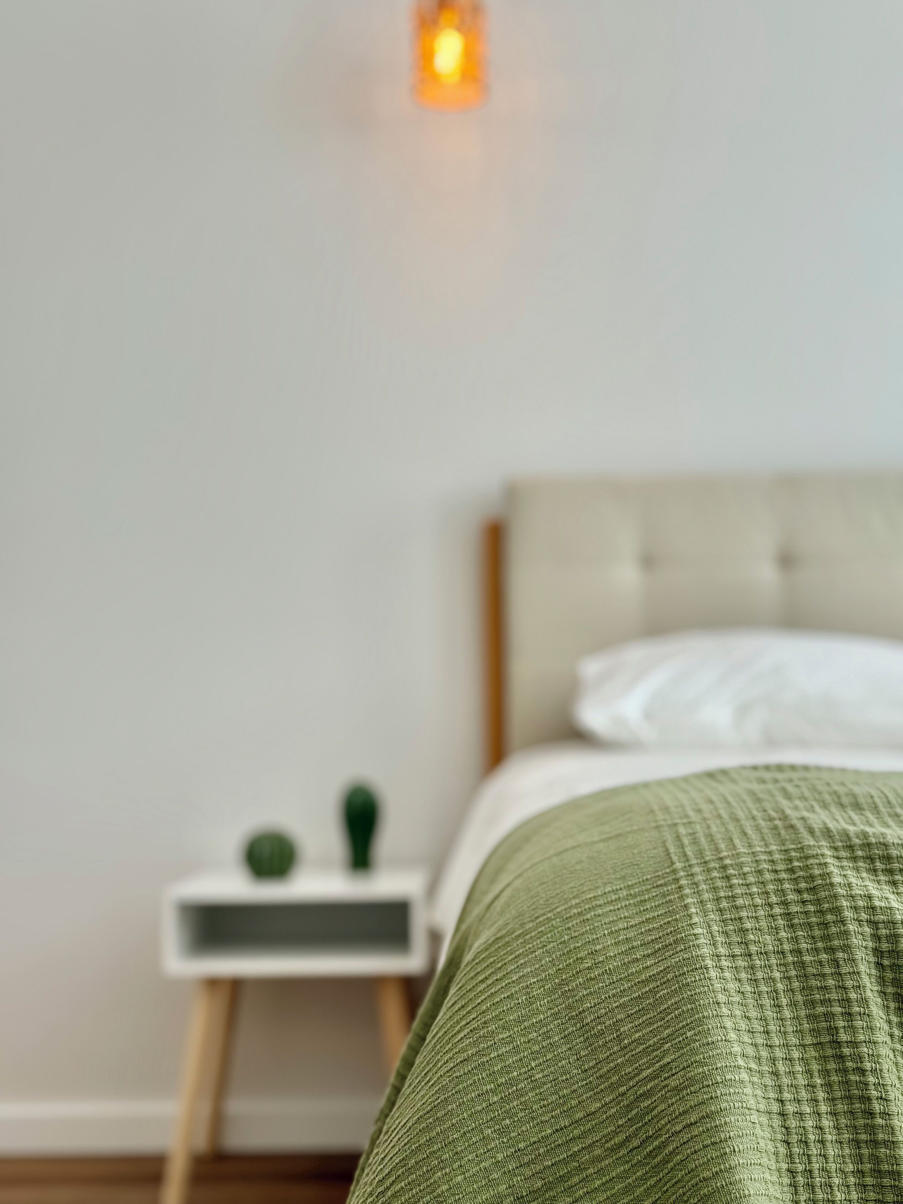Un dormitorio con cama, mesita de noche y una lámpara de pared.