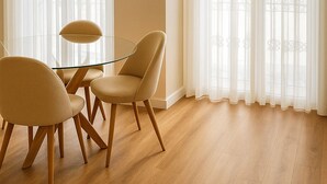 Un comedor con una mesa de vidrio, cuatro sillas y una lámpara colgante.