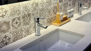 Baño con dos lavamanos, un espejo y un respaldo de azulejos decorativos.