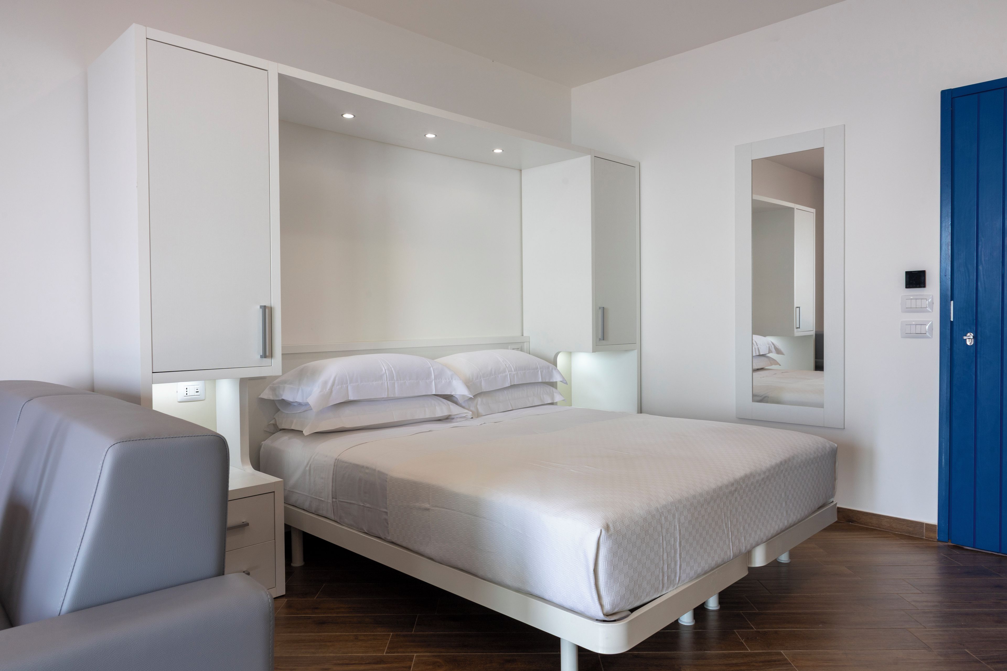 Quarto moderno com cama, mesas de cabeceira, uma cadeira e guarda-roupa.