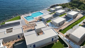 Ein moderner Gebäudekomplex mit Schwimmbad, Solaranlage und Meerblick.