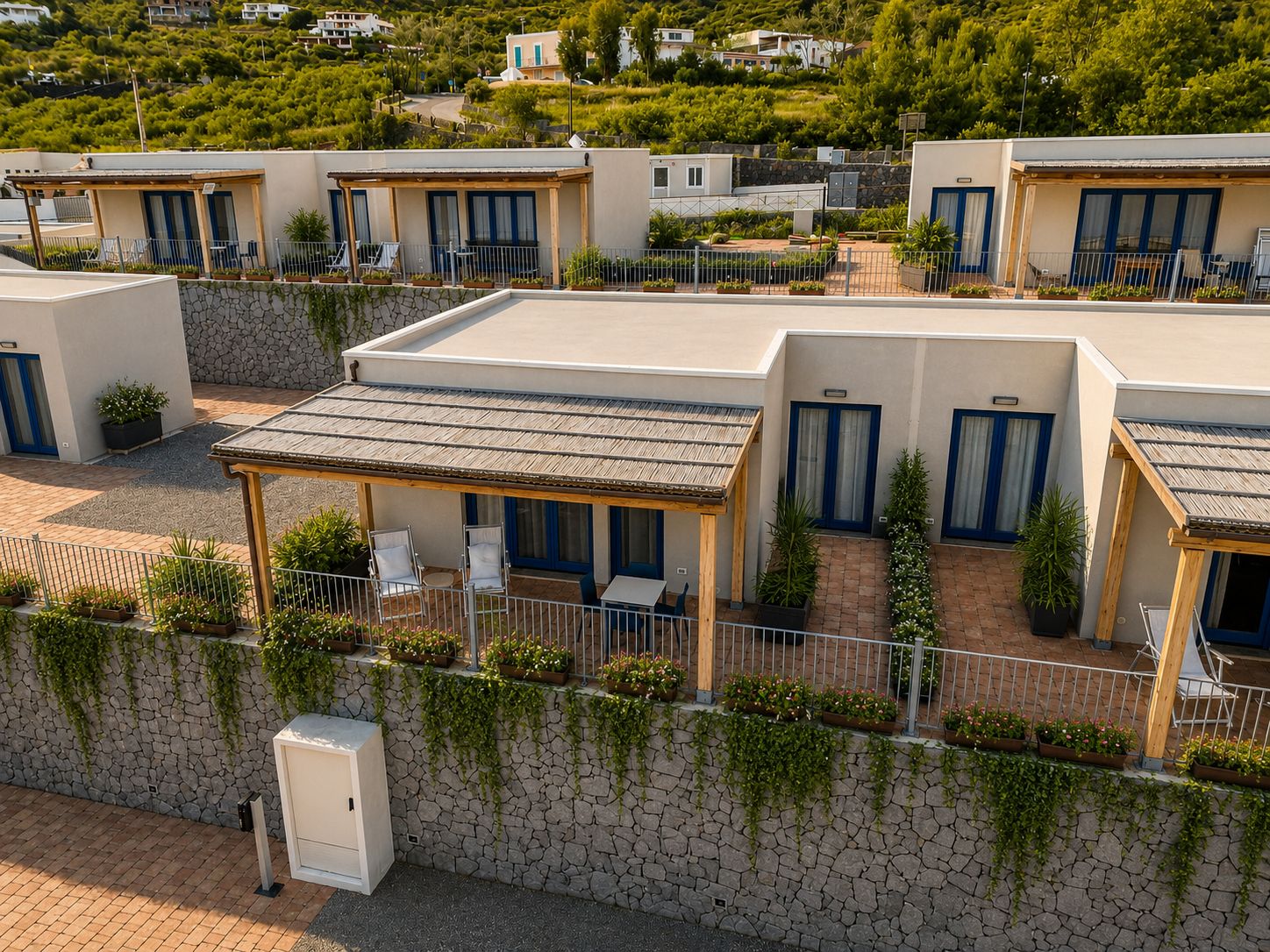 A row of modern, single-story buildings with individual patios, each featuring a wooden pergola and a seating area.