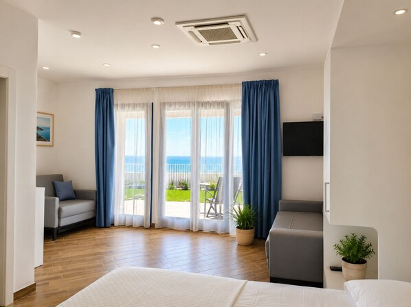 A hotel room with a bed, a sofa, a TV, and a balcony with a view of the sea. - L'Ariana Glamping & Village (leni)