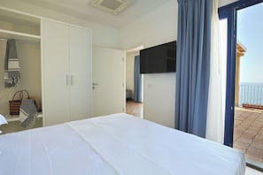 A hotel room with a bed, a wardrobe, a television, and a view of the sea. - L'Ariana Glamping & Village (leni)