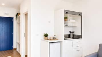A compact kitchen with white cabinets, a built-in oven, and a small refrigerator.