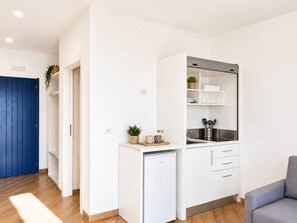 A compact kitchen with white cabinets, a built-in oven, and a small refrigerator. - L'Ariana Glamping & Village (leni)