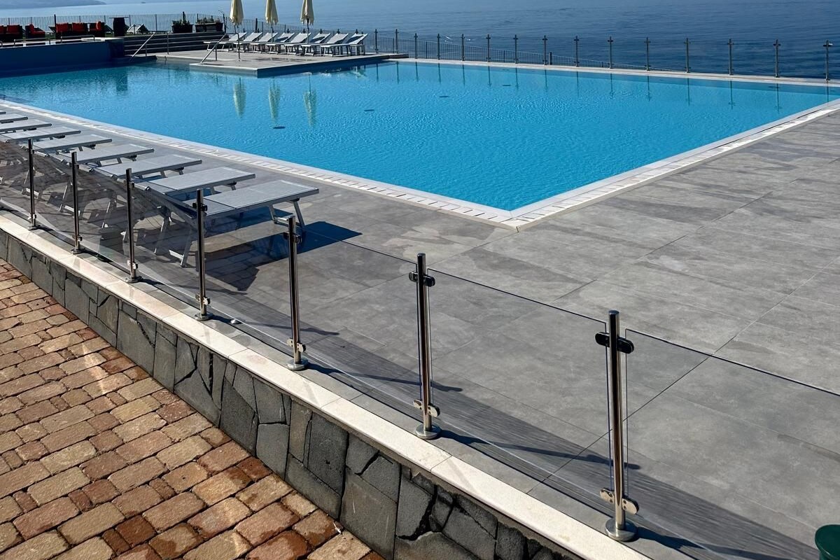Piscina azul cristalina con vistas al mar y montañas al fondo.