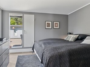 Un dormitorio con cama, cómoda y puerta que da a un balcón.