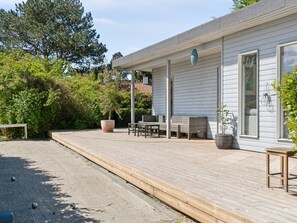 Un espacio al aire libre techado con piso de madera, asientos y plantas en macetas.