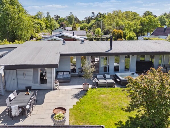 Una casa moderna con un patio que incluye una mesa de comedor, sillas y un jacuzzi.