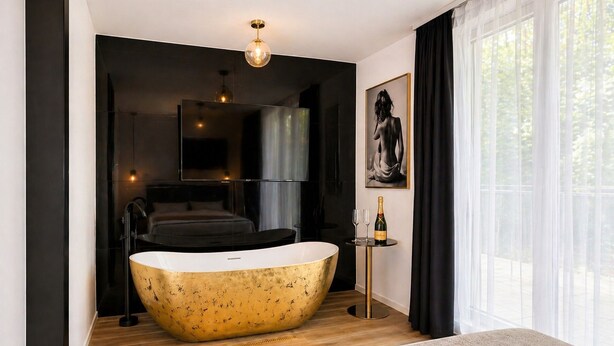 Een moderne badkamer met een vrijstaand bad, een grote spiegel en een inlijsting geplaatst kunstwerk aan de muur.
