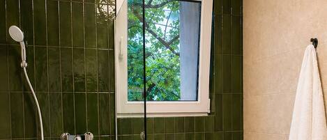 Ein Badezimmer mit Duschkabine, Toilette, Fenster mit Blick und Handtuchhalter.