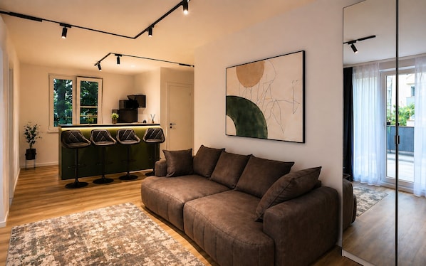A modern living room with a brown sofa, a green bar area, and a large abstract painting on the wall. - Arena Park Bucharest (Bucharest)