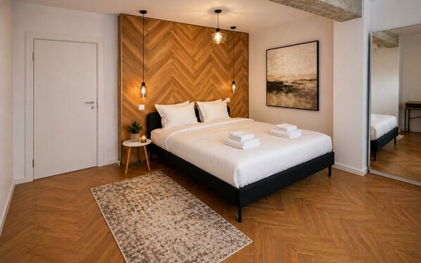 A bedroom with a wooden herringbone wall, a bed with white bedding, two pendant lights, a small bedside table with a plant, and a large abstract painting on the wall. - Arena Park Bucharest (Bucharest)