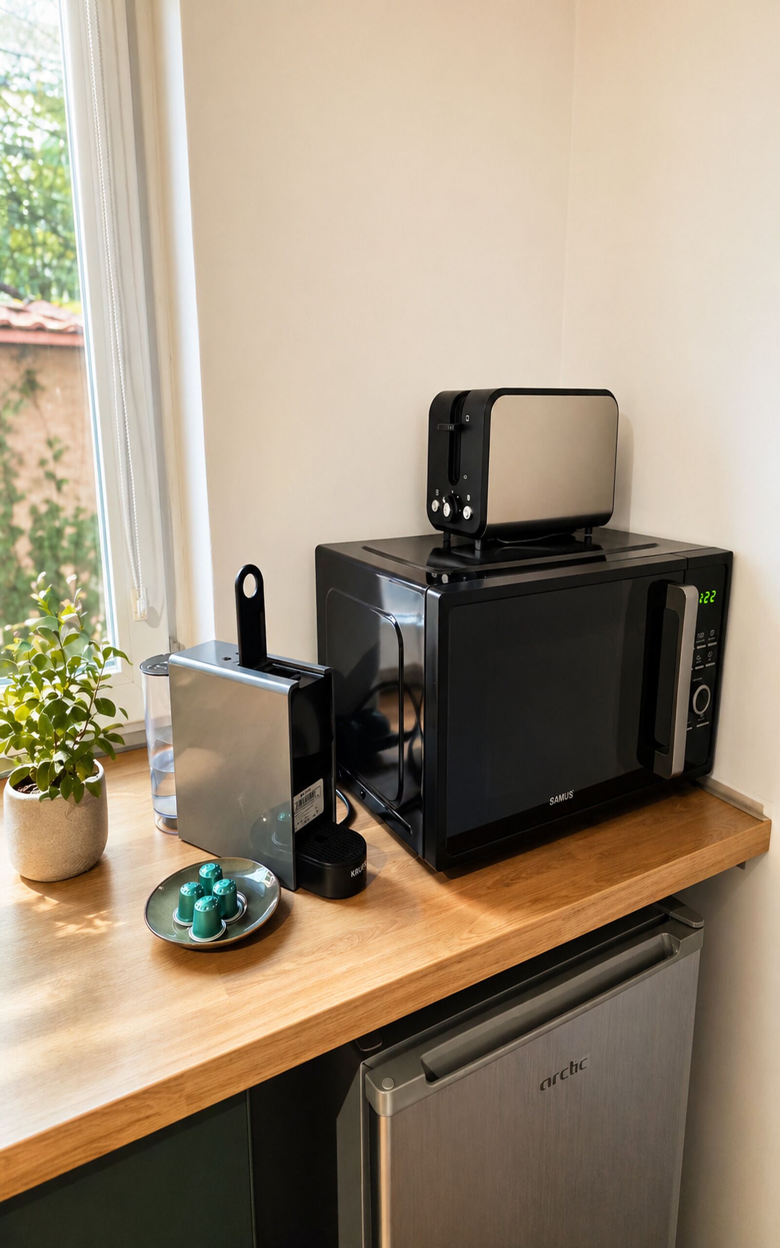 Une cuisine équipée d’un four à micro-ondes, d’un grille-pain et d’une machine à café, le tout posé sur un plan de travail en bois.