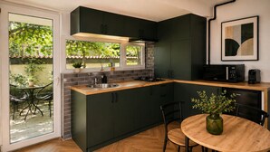 Een moderne keuken met donkere kastjes, een houten aanrecht, een spoelbak en een eethoek met stoelen en een tafel.