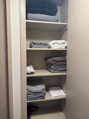 A closet with shelves holding folded towels in various colors.