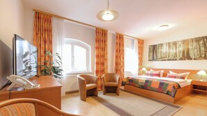 A hotel room with a bed, two armchairs, a desk with a telephone, and a large window. - Altwernigeröder Apparthotel  (Wernigerode)