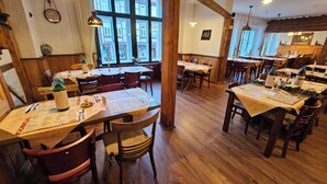 A restaurant with wooden tables and chairs, large windows, and a rustic interior. - Altwernigeröder Apparthotel  (Wernigerode)