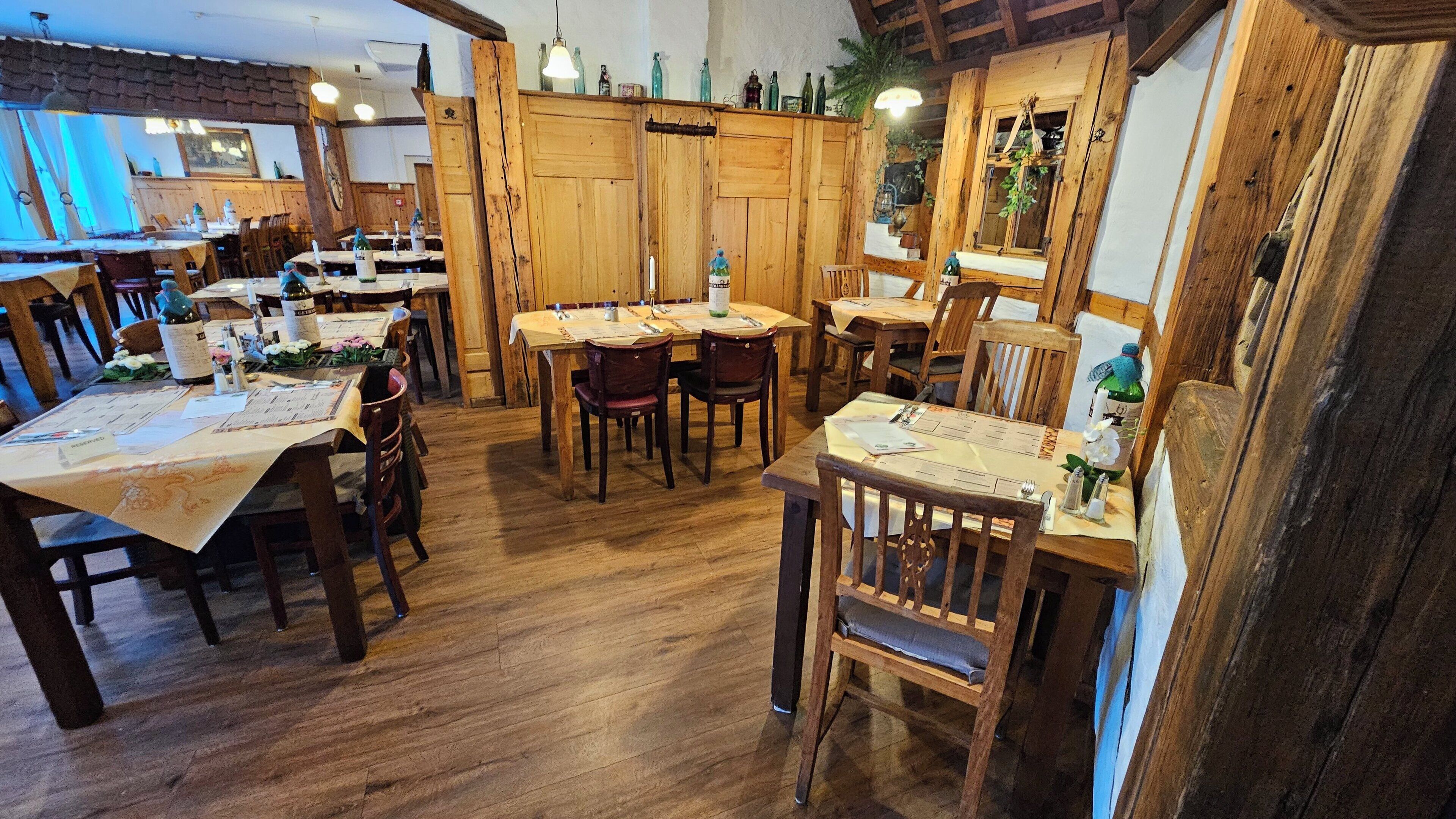 A restaurant with wooden tables and chairs, a brick wall, and hanging light fixtures.