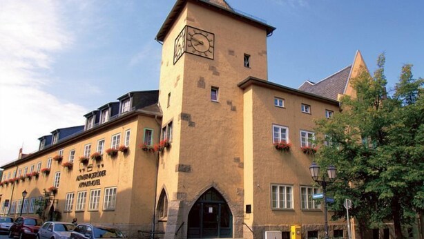 A historic building with a clock tower, multiple windows, and a sign for 'Altenburg Hotel'.