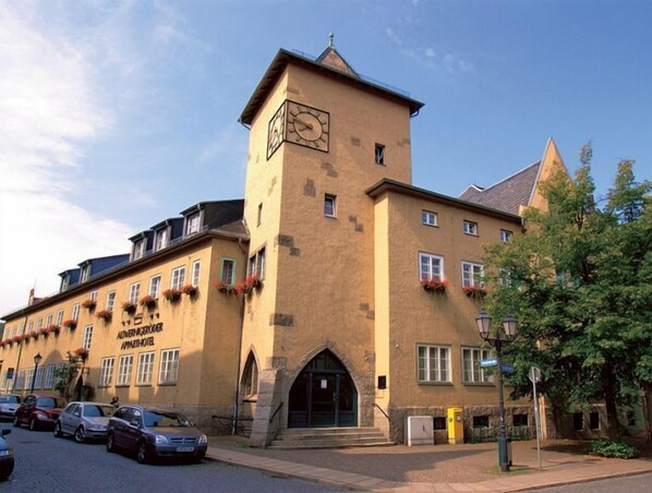 A historic building with a clock tower, multiple windows, and a sign for 'Altenburg Hotel'.