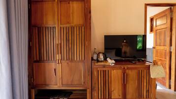 Un meuble en bois sur lequel sont posés une télévision, un téléphone et une cafetière, le tout sur une table en bois.