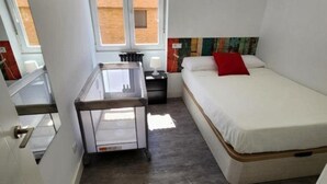 Una habitación pequeña con cama, escritorio y ventana.