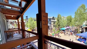 A view from a balcony overlooking a bustling outdoor plaza with wooden railings and a clear blue sky. - Black Bear 8040 (Keystone)