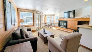 A cozy living room with a sofa, armchairs, a coffee table, and a fireplace. - Lakeside 1488 (Keystone)