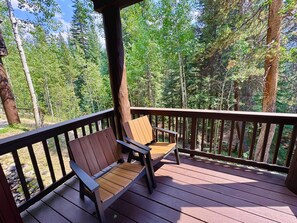 A wooden deck with a bench and a railing, surrounded by a forested area. - Trappers Crossing 8769 (Keystone)
