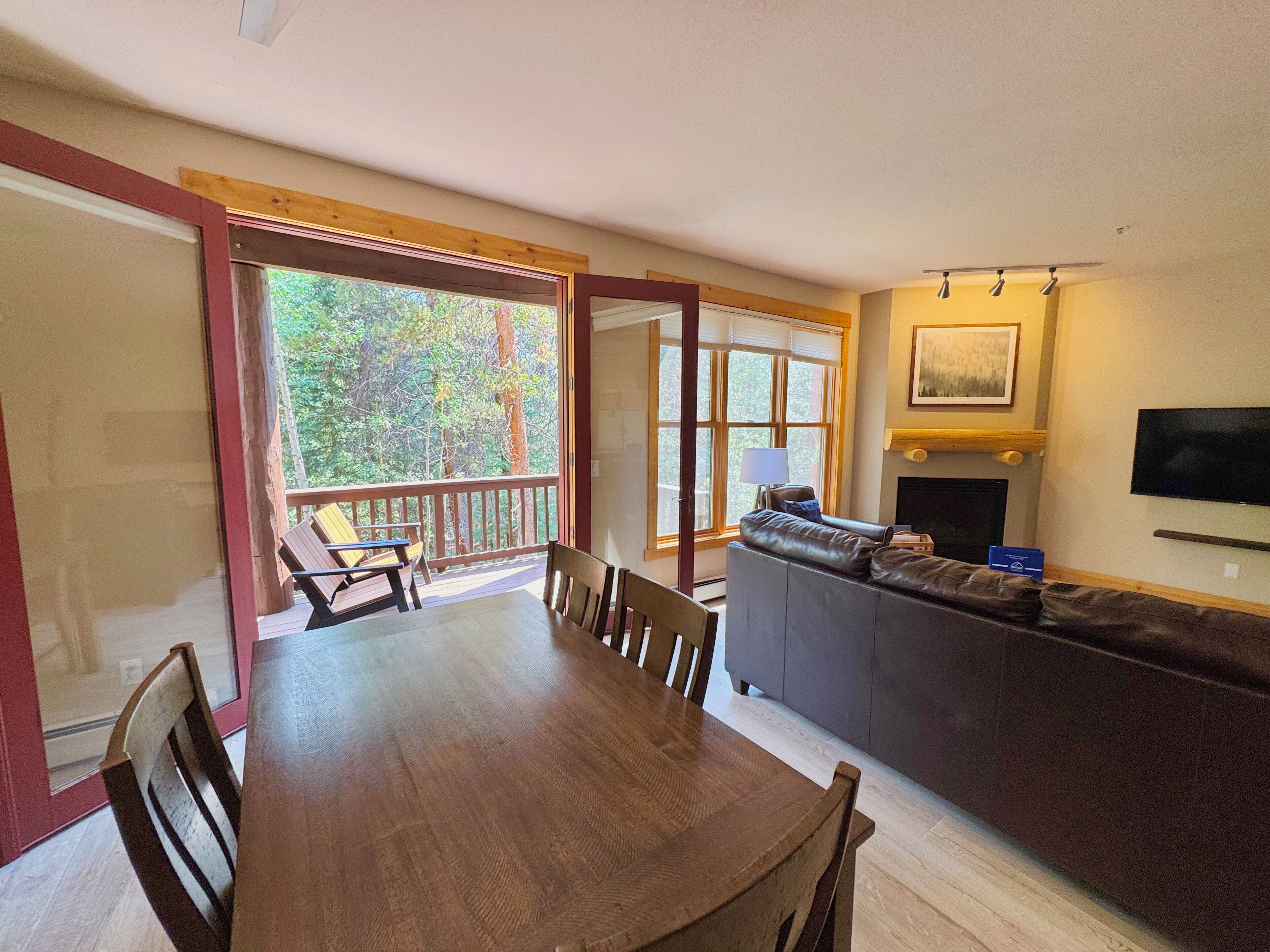 A dining area with a wooden table and chairs, a sofa, and a TV mounted on the wall.