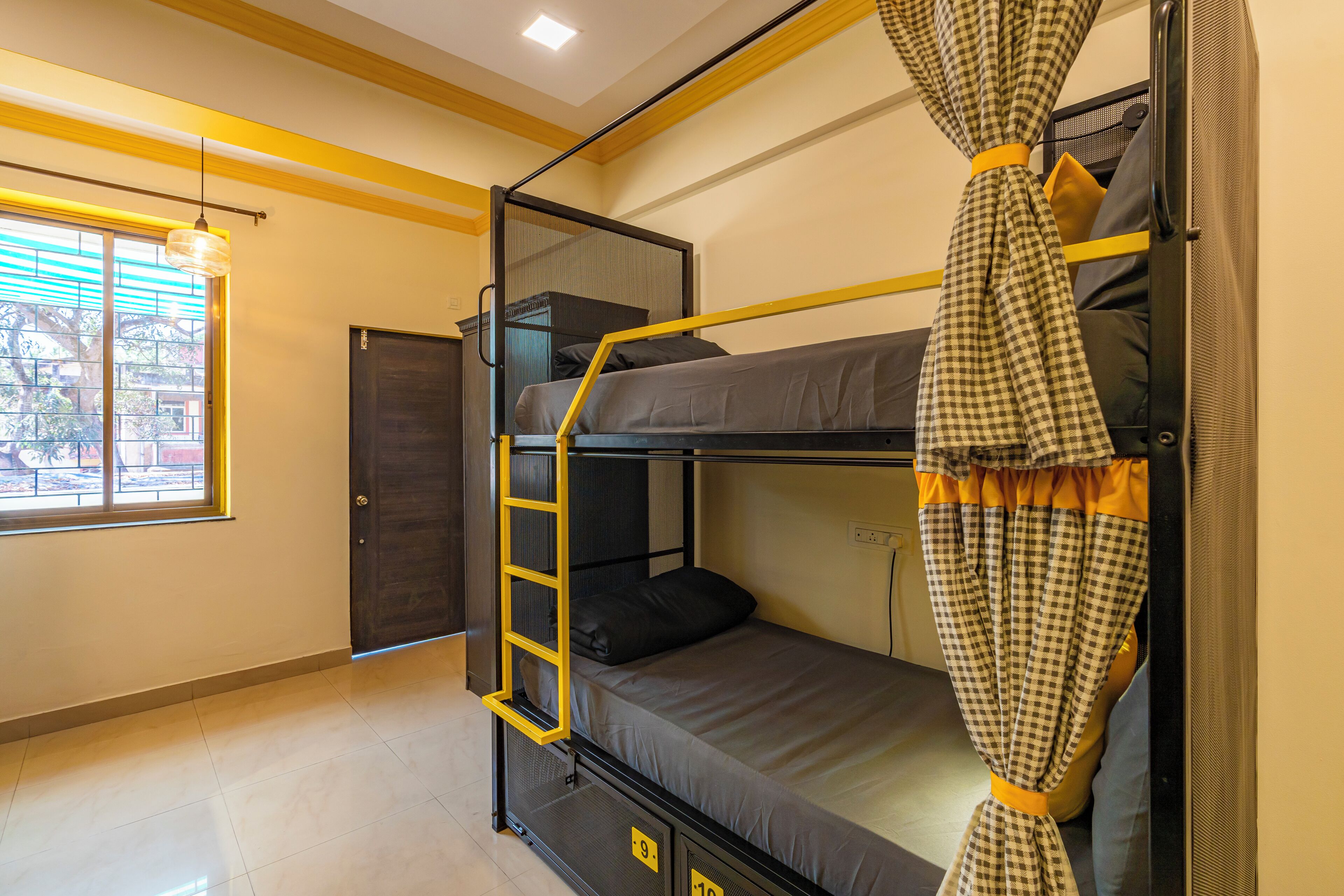 Habitación con literas, ventana, puerta y escalera amarilla.
