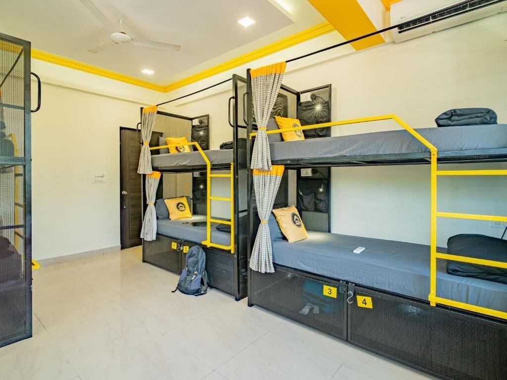 A dormitory room with bunk beds, a ceiling fan, and a door with a mesh screen.
