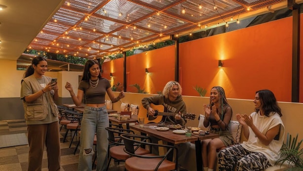 A group of people in a restaurant with a modern interior, including a ceiling with lights and a wall with a warm color scheme.