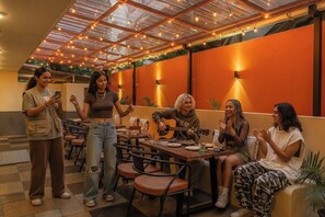 A group of people in a restaurant with a modern interior, including a ceiling with lights and a wall with a warm color scheme. - The Hosteller Goa, Candolim (Candolim)