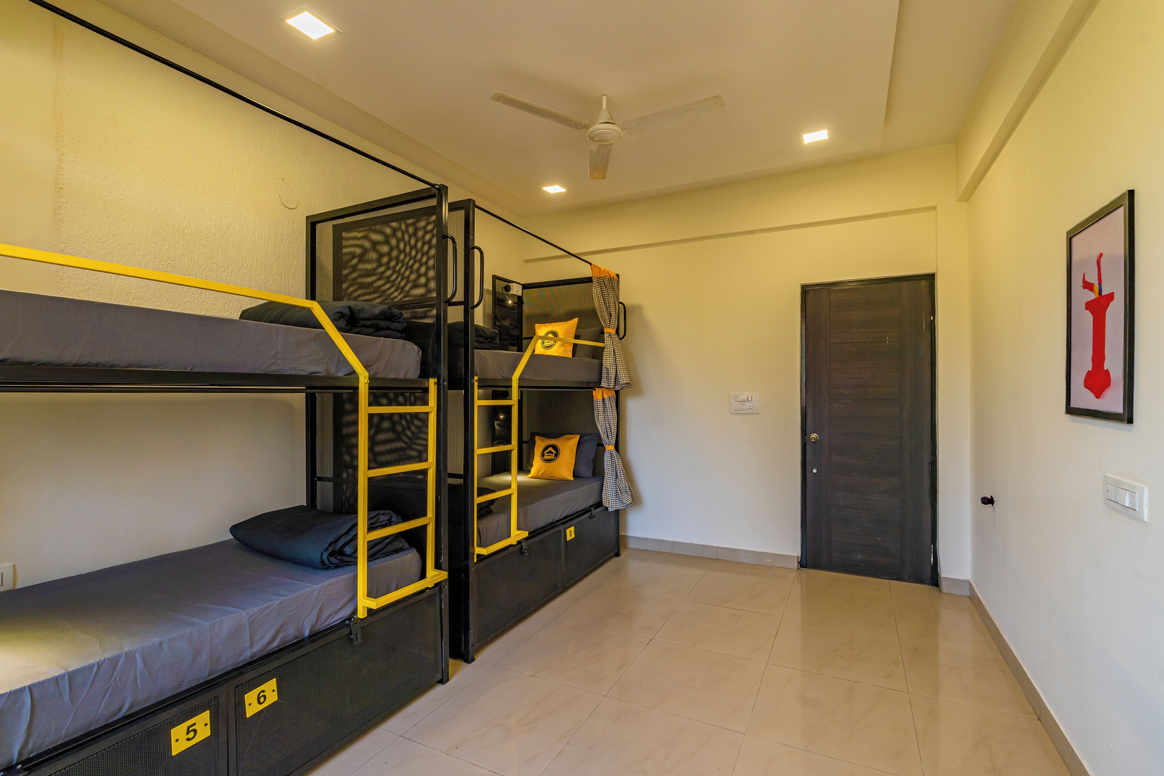 A dormitory room with bunk beds, a ceiling fan, and a door.