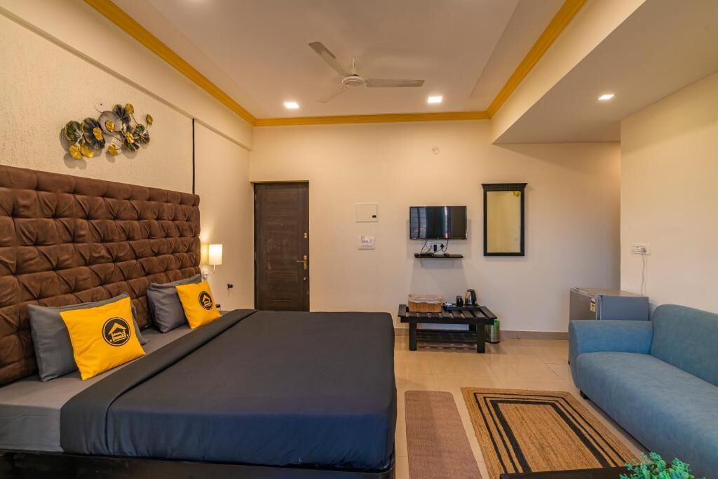 A hotel room with a large bed, a sofa, a TV, and a ceiling fan.