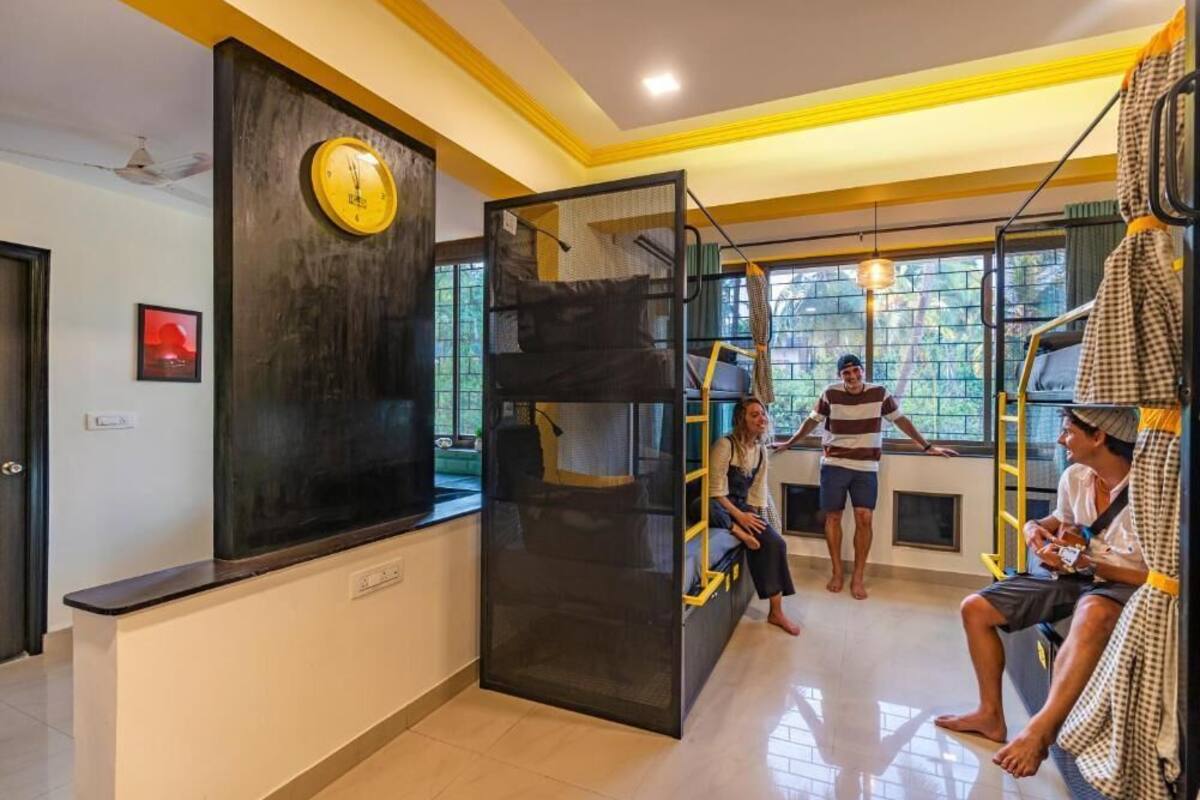 A room with bunk beds, a clock on the wall, and a window with a view of trees.