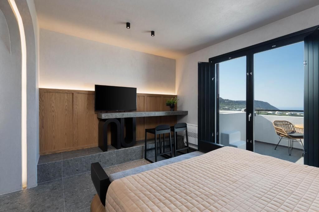 Una camera da letto moderna con un letto, una scrivania con televisione e un balcone vista.