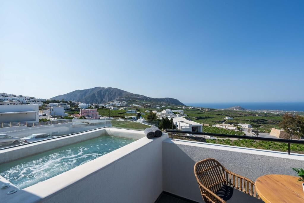 A rooftop terrace with a hot tub, a wicker chair, and a table.