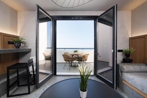 Una sala de estar moderna con un ventanal corredizo que da a un balcón con mobiliario exterior.
