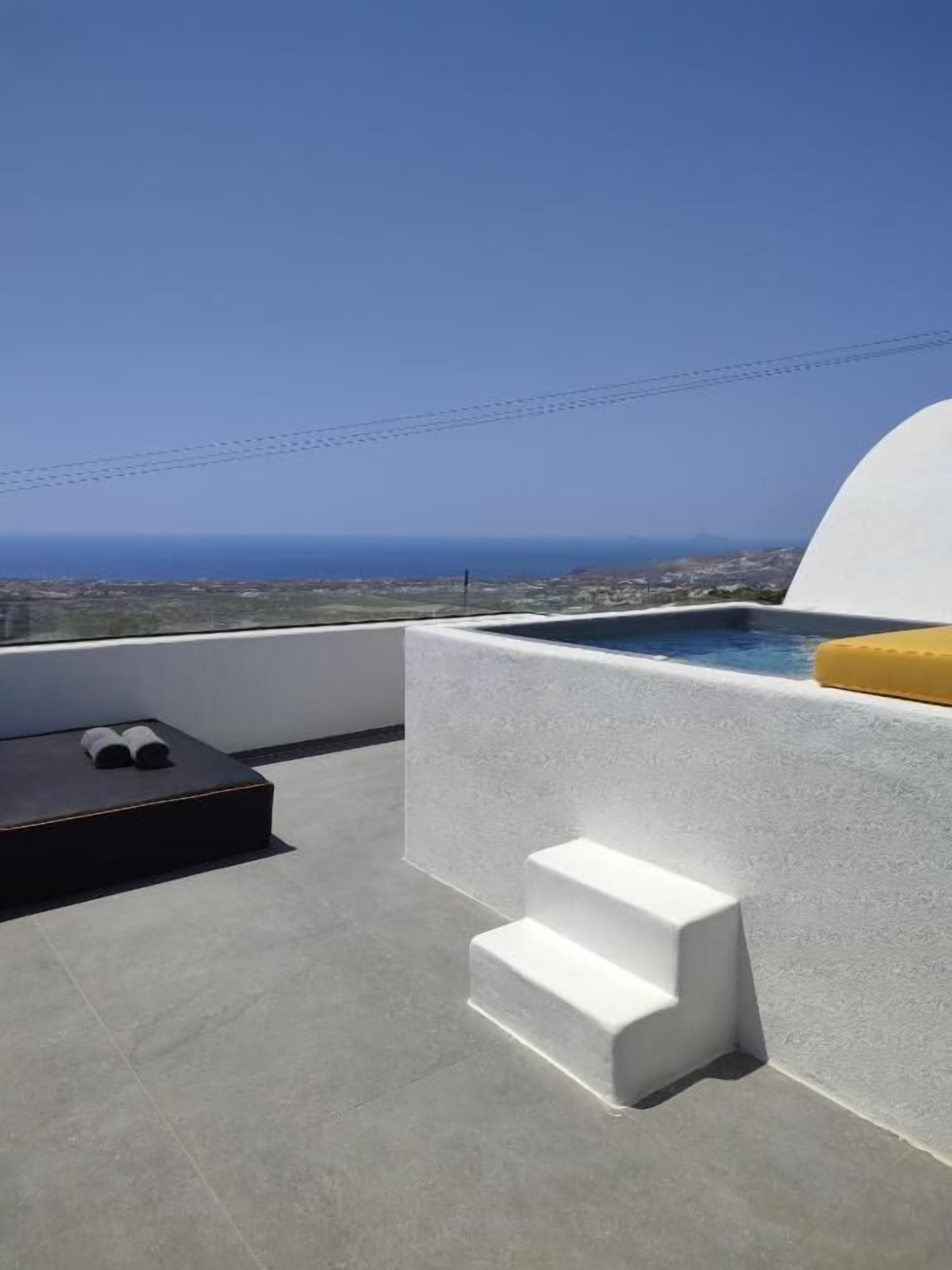 A rooftop terrace with a pool, a sun lounger, and a view of the ocean.