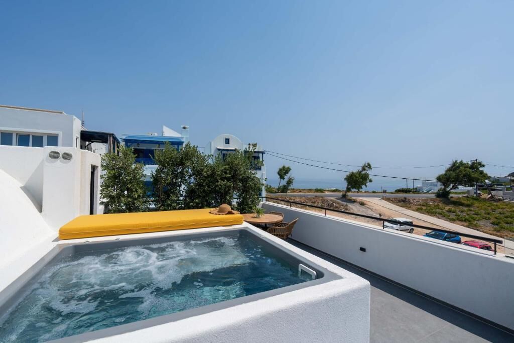 Un espace piscine aménagé sur le toit, avec un transat jaune, entouré de murs blancs et offrant une vue dégagée sur la mer.