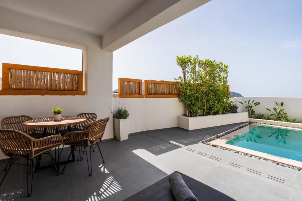 Una terraza en la azotea con piscina, muebles de mimbre y plantas en macetas.